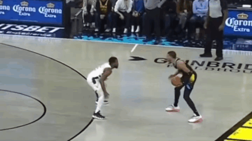 two men are playing basketball on a court with corona extra advertisements on the sidelines