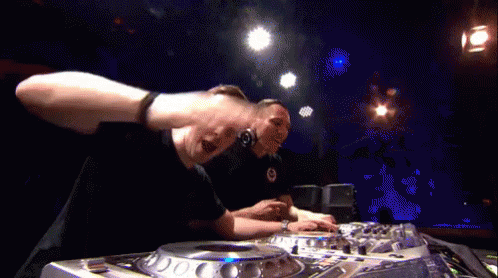 Two Men Are Playing Music In A Dark Room With Blue Lights Behind Them GIF