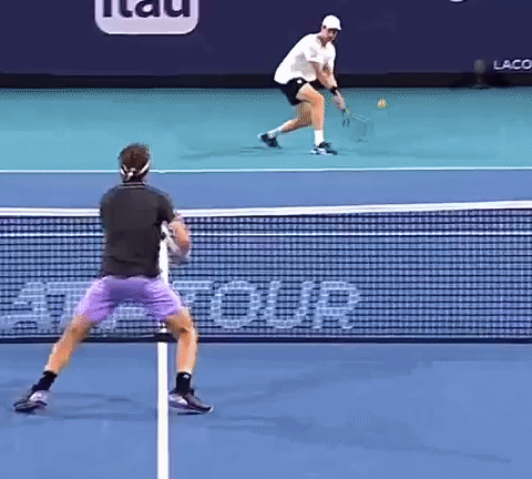 two men are playing tennis on a court with a sign that says tour