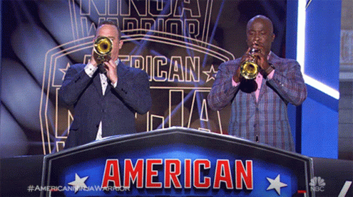 Two Men Are Playing Trumpets In Front Of A Banner That Says American GIF