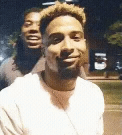Two Men Are Posing For A Picture Together And One Of Them Is Smiling . GIF