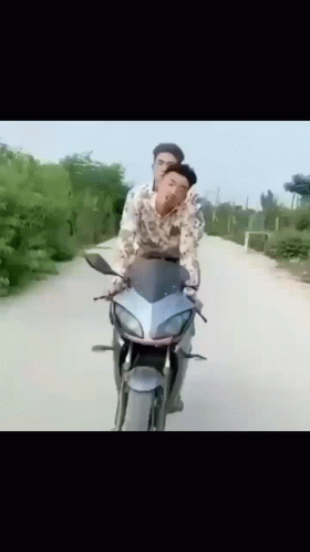 Two Men Are Riding A Motorcycle On A Road GIF