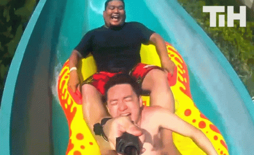 Two Men Are Riding Down A Water Slide With The Letters Th Visible In The Background GIF