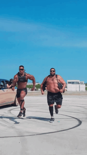 Two Men Are Running In A Parking Lot With One Wearing A Weighted Vest GIF