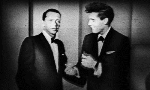 Two Men Are Shaking Hands In A Black And White Photo . GIF