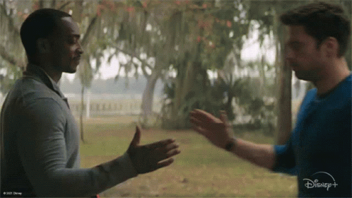 Two Men Are Shaking Hands In Front Of A Disney + Logo GIF