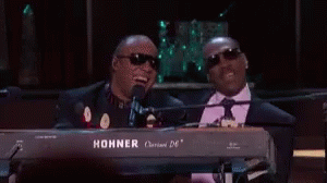 Two Men Are Sitting At A Keyboard And One Of Them Is Wearing Sunglasses . GIF