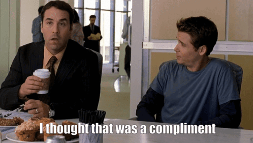 Two Men Are Sitting At A Table And One Of Them Is Saying " I Thought That Was A Compliment " GIF