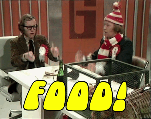 Two Men Are Sitting At A Table And The Word Food Is On The Screen GIF