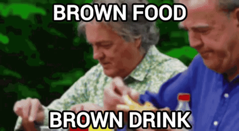 Two Men Are Sitting At A Table Eating Food And Drinking Brown Drinks GIF