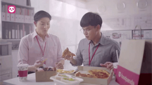 Two Men Are Sitting At A Table With Boxes Of Food And A Bag That Says Foodpanda On It GIF