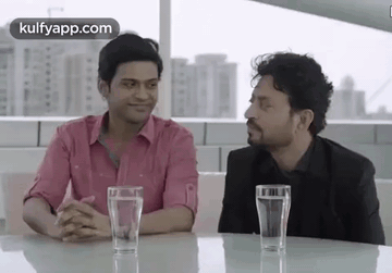 Two Men Are Sitting At A Table With Glasses Of Water In Front Of Them . GIF