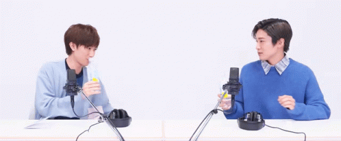 Two Men Are Sitting At A Table With Microphones And Headphones . GIF