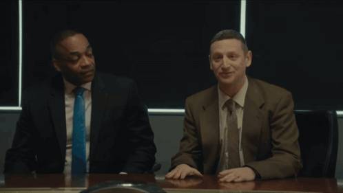 Two Men Are Sitting At A Table With The Words Coward Pig Flick On The Bottom GIF