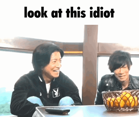 Two Men Are Sitting At A Table With The Words Look At This Idiot Written Above Them GIF