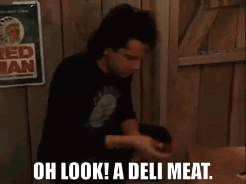 Two Men Are Sitting At A Table With The Words Oh Look A Deli Meat Written On The Screen GIF