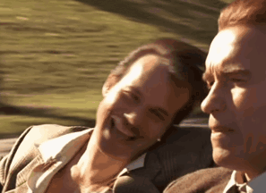 Two Men Are Sitting In A Car And Smiling At Each Other . GIF
