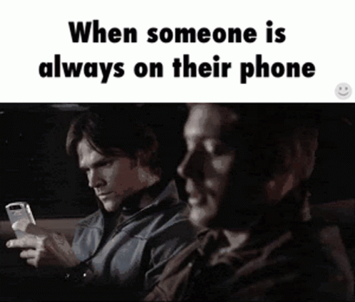 Two Men Are Sitting In A Car Looking At Their Phones And The Caption Says When Someone Is Always On Their Phone GIF