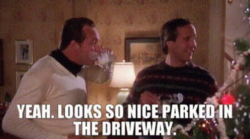 Two Men Are Sitting In Front Of A Christmas Tree Drinking Wine And Talking . GIF
