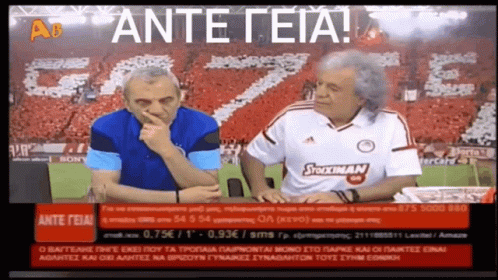 Two Men Are Sitting In Front Of A Screen That Says " Ante Teia " On It GIF