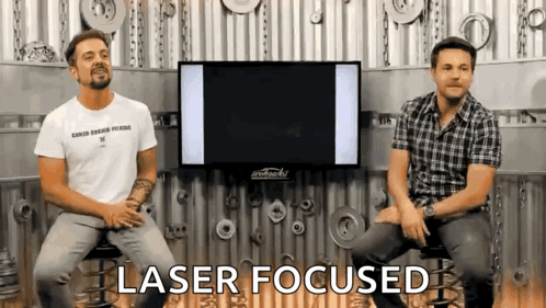 Two Men Are Sitting In Front Of A Tv And The Words Laser Focused Are Visible GIF