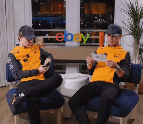 Two Men Are Sitting In Front Of An Ebay Logo GIF