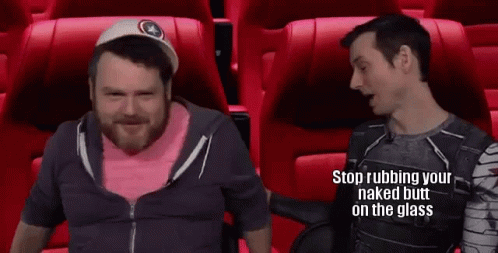Two Men Are Sitting In Red Seats In A Movie Theater Talking . GIF