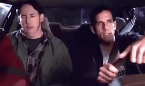 Two Men Are Sitting In The Back Seat Of A Car And One Of Them Is Pointing At The Camera . GIF