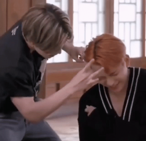 Two Men Are Sitting Next To Each Other And One Of Them Is Touching The Other 'S Head . GIF