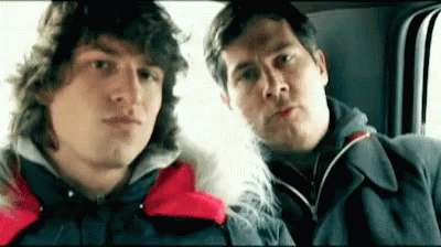 Two Men Are Sitting Next To Each Other In A Car Looking At The Camera . GIF
