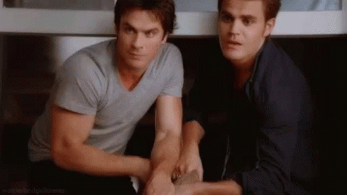 Two Men Are Sitting Next To Each Other In A Room Holding Hands . GIF