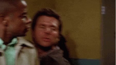 Two Men Are Sitting Next To Each Other In A Room . One Of The Men Is Kissing The Other On The Cheek . GIF