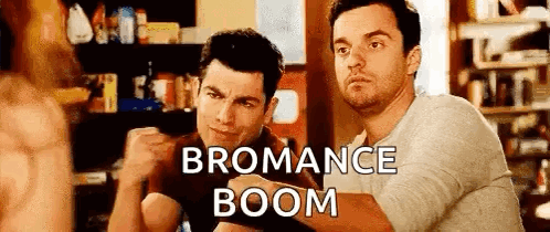 Two Men Are Sitting Next To Each Other In A Room With The Words `` Bromance Boom '' Written On The Bottom . GIF