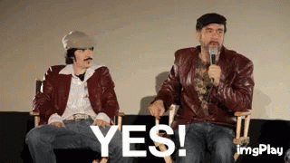 Two Men Are Sitting Next To Each Other On A Couch And One Is Holding A Microphone And The Other Is Saying Yes . GIF