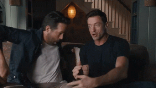 Two Men Are Sitting On A Couch And One Of Them Is Wearing A Blue Shirt GIF