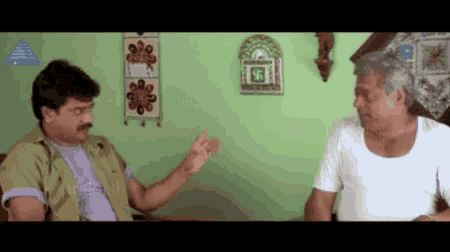 Two Men Are Sitting On A Couch And Talking To Each Other . GIF
