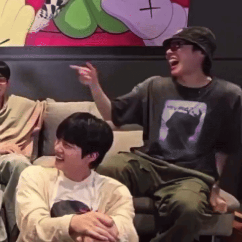 Two Men Are Sitting On A Couch Laughing And One Is Pointing At The Camera . GIF