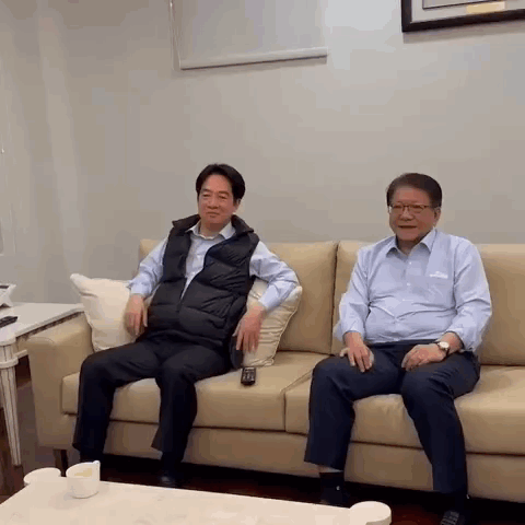 Two Men Are Sitting On A Couch With A Remote Control . GIF