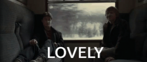 two men are sitting on a couch with the word lovely in the corner