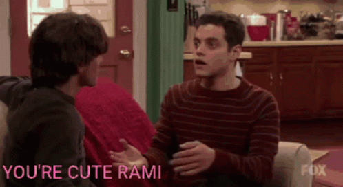 Two Men Are Sitting On A Couch With The Words You 'Re Cute Rami Written On The Bottom GIF