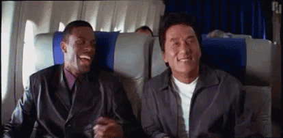 two men are sitting on a plane laughing .