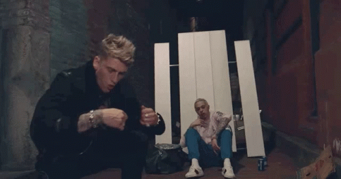 Two Men Are Sitting On The Ground And One Is Smoking A Cigarette . GIF