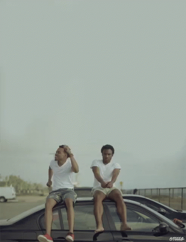 Two Men Are Sitting On The Roof Of A Car With The Letters Steccs On The Bottom Right GIF