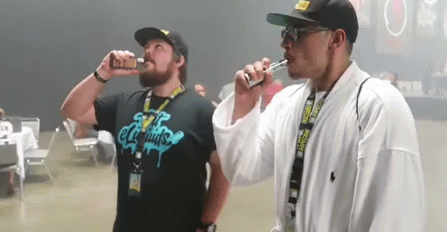 two men are smoking electronic cigarettes and one has a shirt that says e liquids on it
