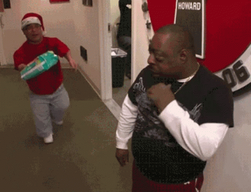 Two Men Are Standing In A Hallway With A Sign That Says Howard GIF