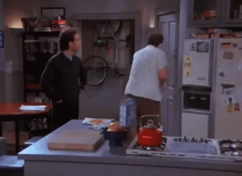 Two Men Are Standing In A Kitchen In Front Of A Refrigerator That Has A Sticker On It That Says ' S. ' GIF