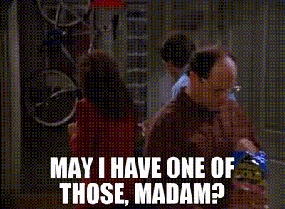Two Men Are Standing In A Kitchen Talking To Each Other . One Of The Men Is Holding A Bag Of Chips . GIF