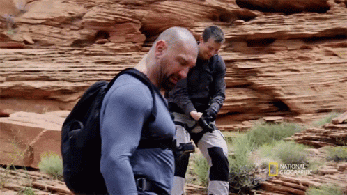 Two Men Are Standing In A Rocky Area With National Geographic Written On The Bottom Right GIF