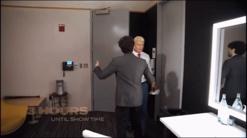 Two Men Are Standing In A Room With The Words 3 Hours Until Show Time On The Wall GIF
