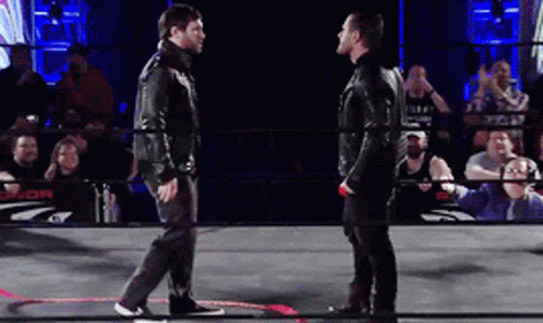 Two Men Are Standing In A Wrestling Ring With A Crowd Behind Them And A Sign That Says J.or. GIF